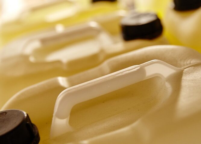 Close-up view of yellow chemical storage containers with black caps and handles arranged in a row.